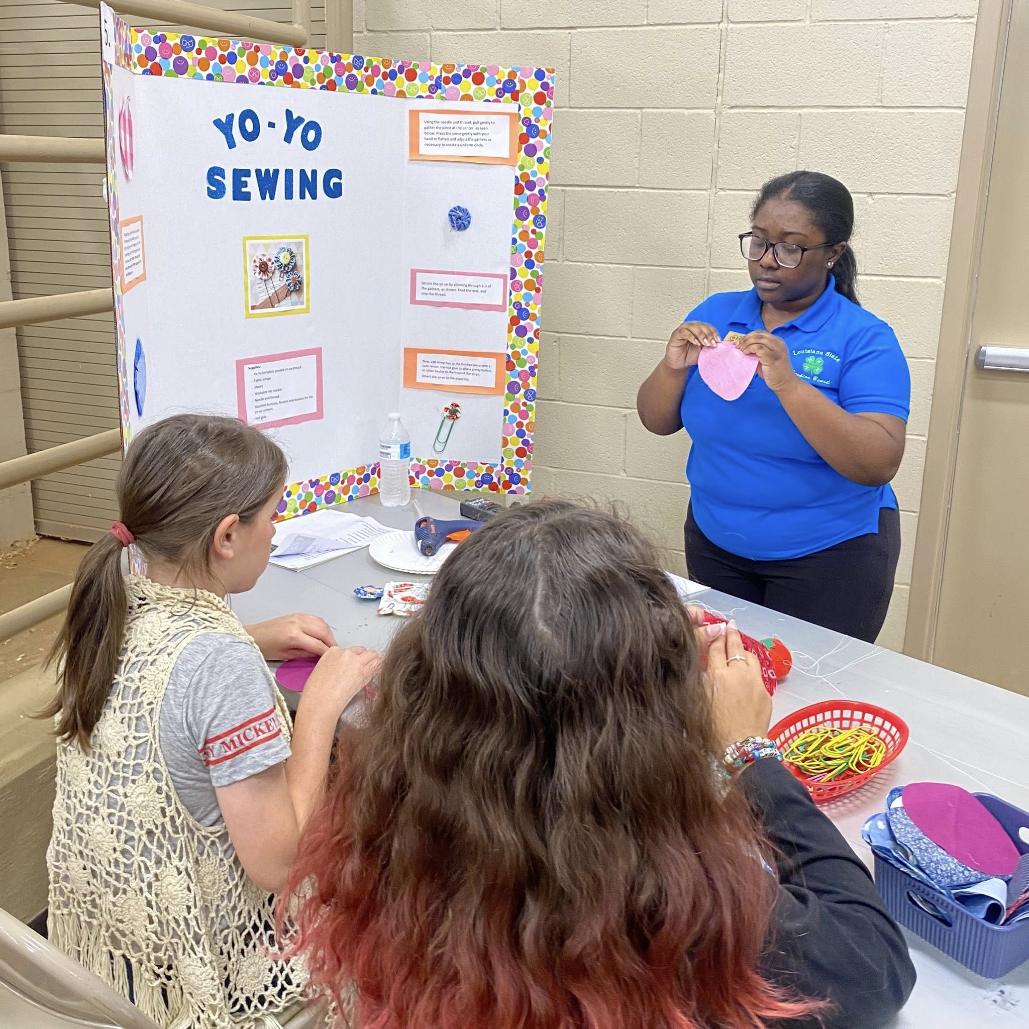 An older girl demonstrating something for two young girls.